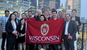 A group of people holding up a UW-Madison flag in front of Toronto's skyline