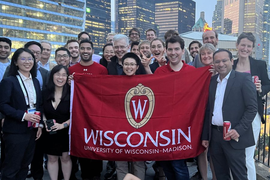 A group of people holding up a UW-Madison flag in front of Toronto's skyline