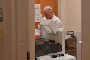 A man in a white lab coat handling a vial.