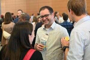 A man in the crowd smiles during conversation at the symposium.