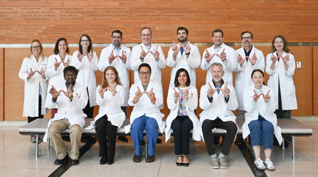 A group of neuroradiology faculty pose together with their hands in a 'W' for Wisconsin.