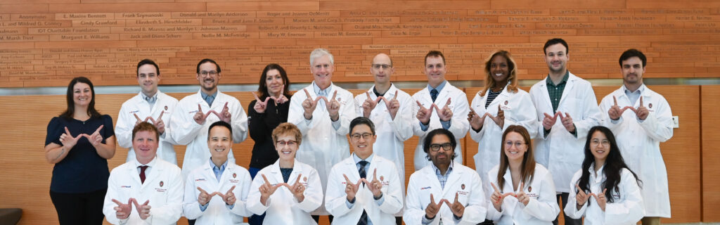 A group of MSK faculty and fellows pose together, holding their hands in a 'W' for Wisconsin.