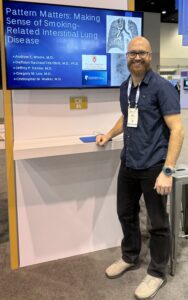 Andrew Moore stands next to a monitor displaying his educational exhibit.